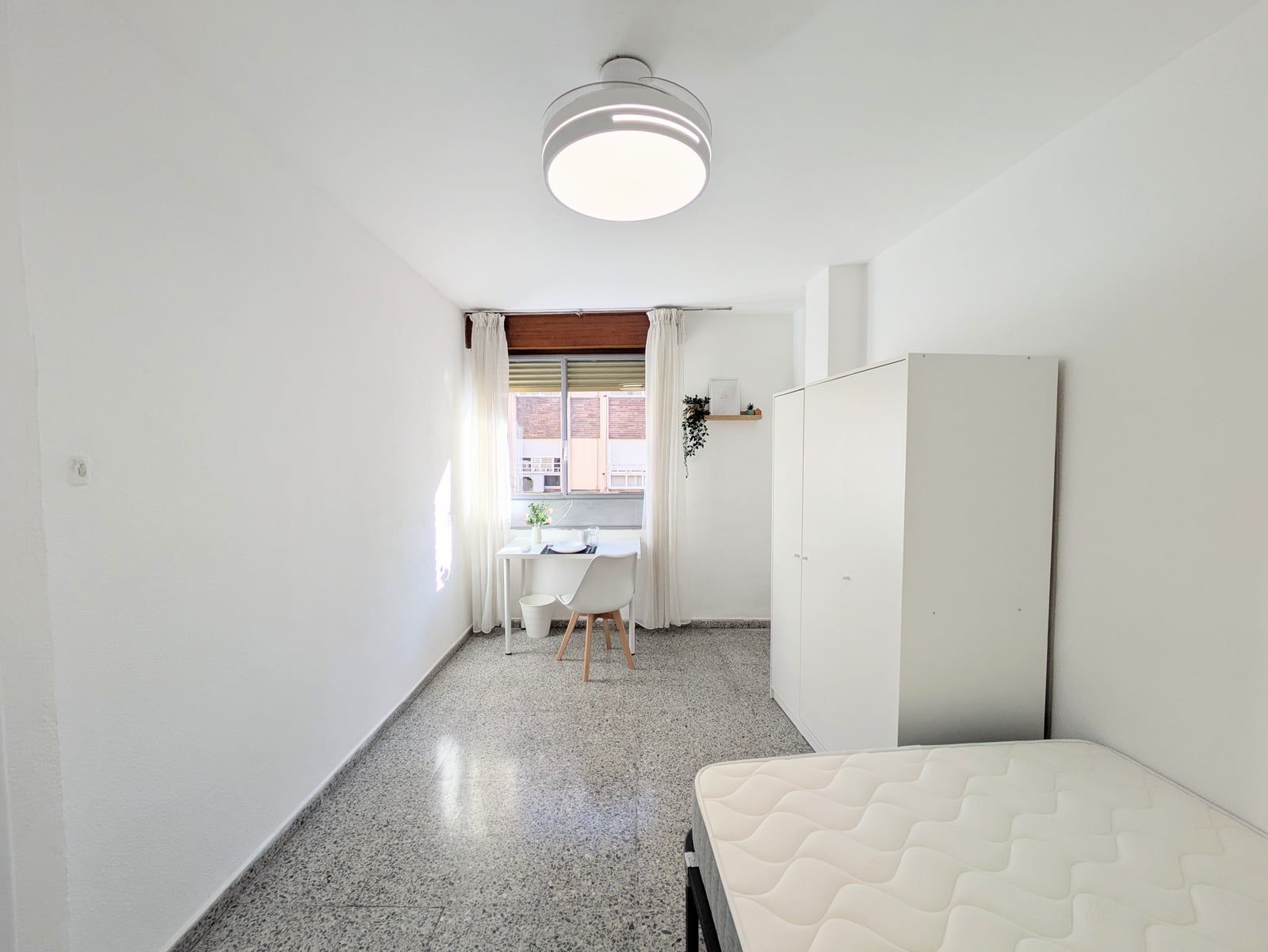 Otra habitación acondicionada, con armario y escritorio junto a la ventana